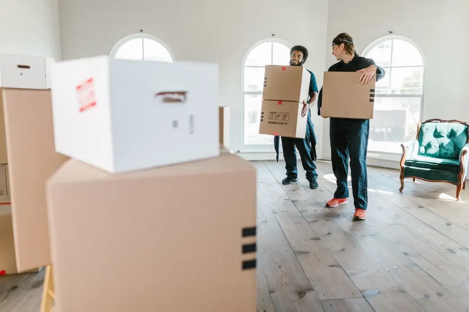 Man and van team carrying moving boxes inside a UK home